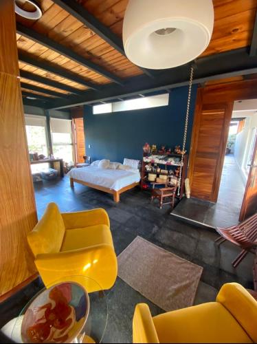 a living room with yellow chairs and a bed at Casa Ilhe Ha in Santa María Tonameca