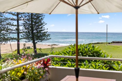 a view of the beach from a balcony with an umbrella at Nautilus Beach Resort by Charlesworth in Coffs Harbour