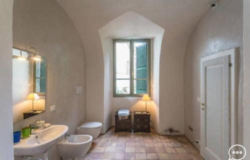 La salle de bains blanche est pourvue d'un lavabo, d'une baignoire et de toilettes. dans l'établissement Casa Gerardi, à Lonato