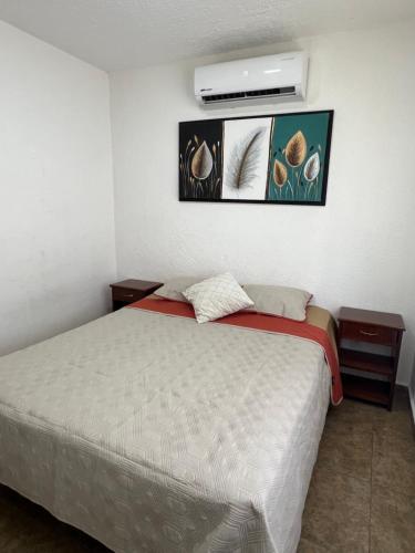 a bedroom with a bed with two pictures on the wall at Departamento en Acapulco Diamante planta baja in La Sabana