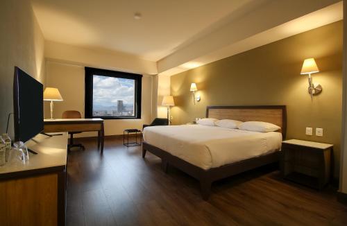 a hotel room with a bed and a desk and a television at Hotel Turotel Morelia in Morelia