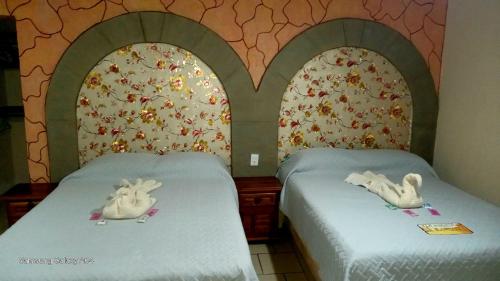 two beds in a room with two swans on them at LA HUERTA Cabaña y Hospedaje in Huasca de Ocampo