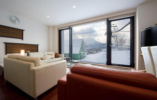 a living room with a couch and a large window at Cecuko A in Kutchan