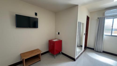 a room with a red cabinet and a tv on a wall at Caminho de Itacoatiara in Niterói