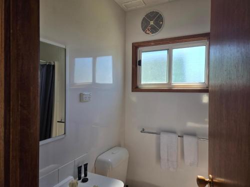 a bathroom with a toilet and a sink and a window at Cooma Holiday Park in Cooma