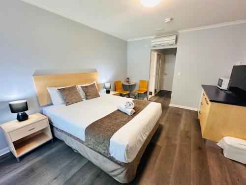 a bedroom with a large bed with a desk and a table at Caloundra Central Apartment Hotel Official in Caloundra