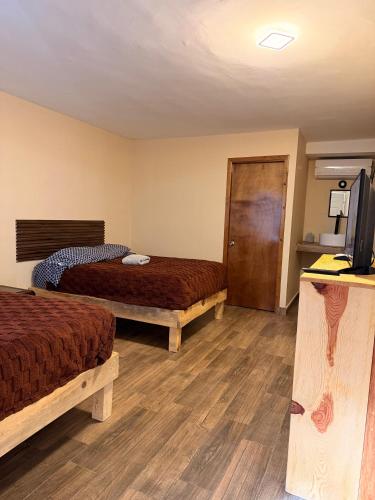 a hotel room with two beds and a flat screen tv at HOTEL Y CABAÑAS El PINO in Creel