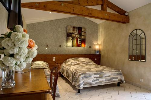 a bedroom with a bed and a table with a vase of flowers at Chambres d'hôtes Les Peyrouses in Sarlat-la-Canéda