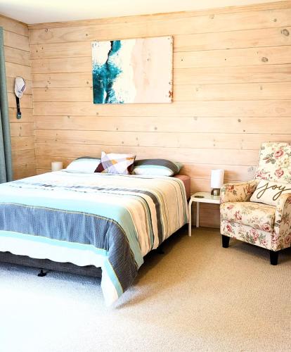 a bedroom with a bed and a chair at Absolute Tranquility - surrounded by native bush in Kaiuma
