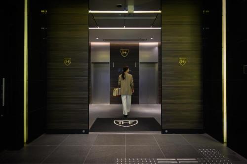 a woman walking through a elevator in a building at The Royal Park Canvas Nagoya in Nagoya