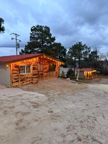 a log cabin with lights on the side of it at Cabañas el Pino 2 in Creel