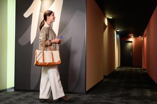 a woman standing in a hallway holding a bag at The Royal Park Canvas Nagoya in Nagoya