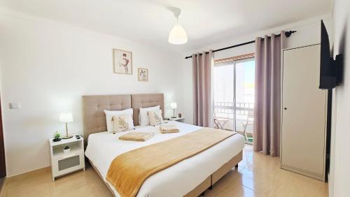 a white bedroom with a bed and a balcony at Baleal Beach Stay in Baleal