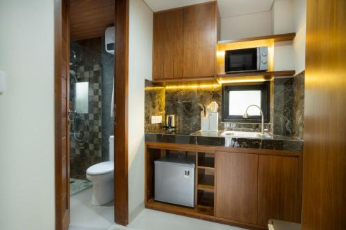 a bathroom with a toilet and a sink and a microwave at Sleepwell Seminyak in Seminyak