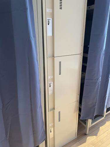 Alt Hostel في مونتريال: غرفة تبديل ملابس بها مرآة وستائر زرقاء