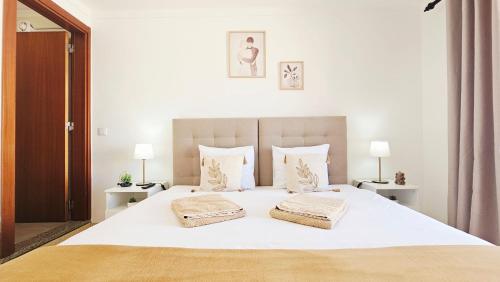 a bedroom with a large white bed with two pillows at Baleal Beach Stay in Baleal