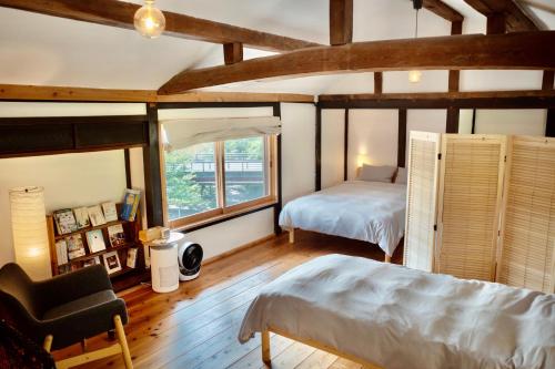 a bedroom with a bed and a chair in a room at HAKURA 築100年古民家一棟貸し 100 Year Old Japanese House Stay in Tamba Sasayama in Sasayama