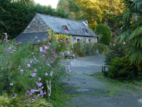 une petite maison en pierre avec des fleurs devant elle dans l'établissement Moulin De Beuzidou, à Saint-Urbain