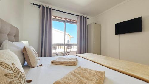 a bedroom with a bed with a tv and a window at Baleal Beach Stay in Baleal