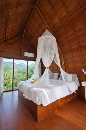 a bedroom with a large bed with a wooden ceiling at The Indah Cliff Sea View in Polilit