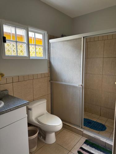 a bathroom with a toilet and a shower with a window at Villa Bonita in La Ceiba