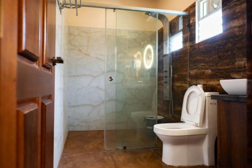 a bathroom with a toilet and a glass shower at Hills Pride in Nandi