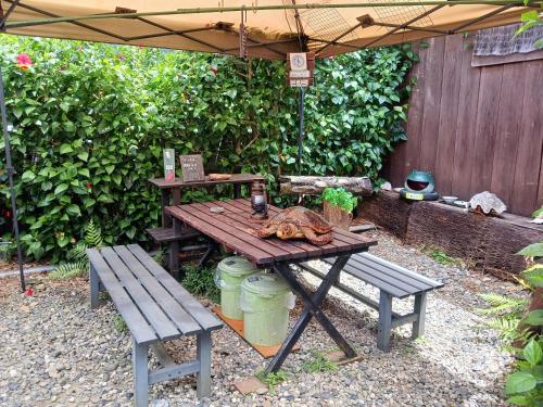a picnic table and two benches under an umbrella at Amami Guest House showa-so in Setouchi