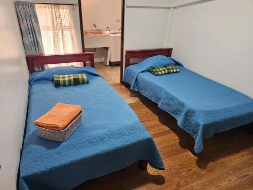two beds in a room with blue blankets and a sink at Apartamento 2 TEC in Cartago