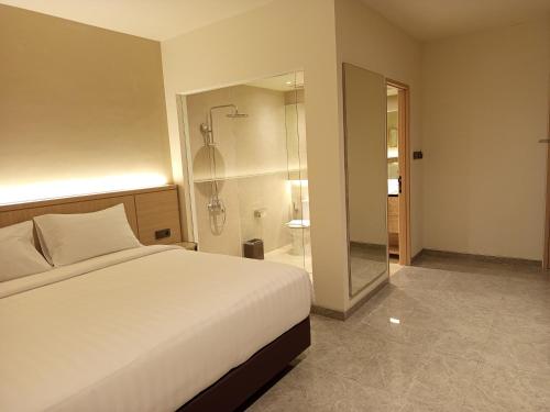 a bedroom with a white bed and a shower at Ow! Hotel Boutique Kemayoran in Jakarta