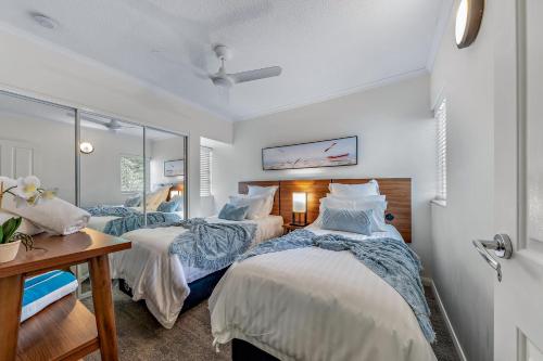 two beds in a room with white walls at Ocean Rise at Airlie Two in Airlie Beach