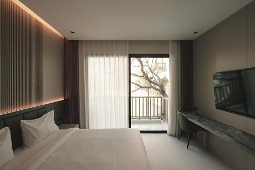 a bedroom with a large bed and a large window at After Rain Hotel in Chiang Mai