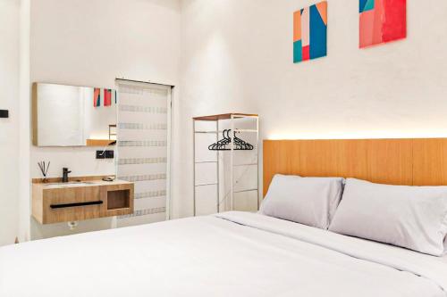 a bedroom with a white bed and a sink at Adi Inn Homestay RedPartner in Sunggal