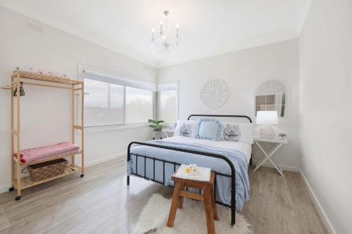 a white bedroom with a bed and a table at Jimley Cottage in Warrnambool