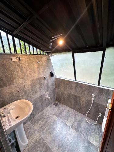 a bathroom with a sink and a toilet and windows at Alpine Heights in Kumburuteniwela