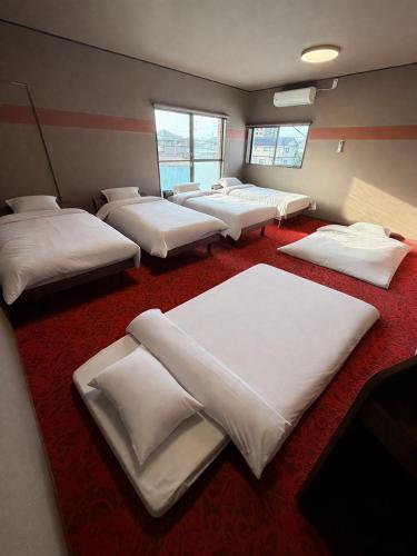 a room with four beds in it with windows at Lento Stay HAGI in Hagi