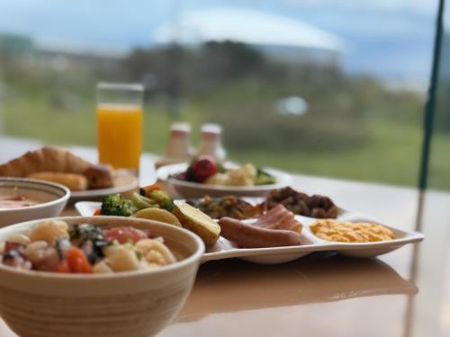 a table with plates of food and a glass of orange juice at Surfeel Hotel Wakkanai in Wakkanai