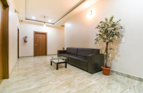 a living room with a black couch and a plant at Hotel Holiday Palace in Sibsāgar