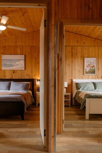 two beds in a room with wooden walls at Sampsons Shack in Vivonne Bay