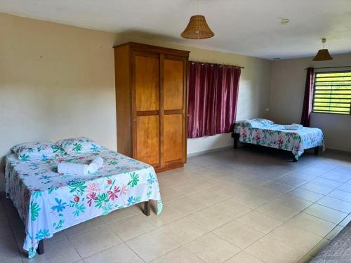 ein Schlafzimmer mit zwei Betten, einem Schrank und einem Fenster in der Unterkunft Rainforest Valley in Mataiea