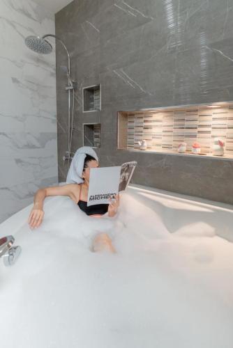 a person laying in a bath tub reading a book at laboon pool villa Pranburi in Ban Nong Ban Kao