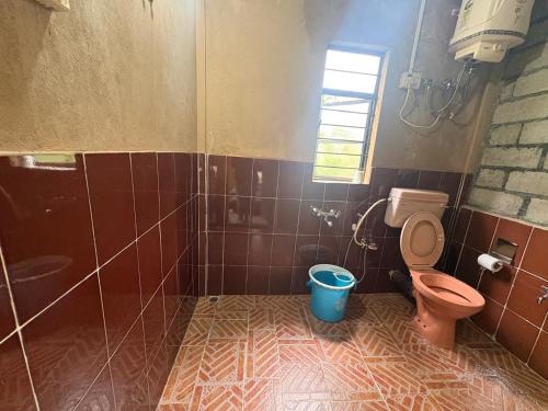 a bathroom with a toilet and a bucket in it at West corner homestay in Shillong