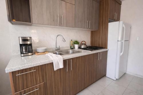 a kitchen with a sink and a white refrigerator at Private Apartment in Prague Poniente Area in Hermosillo