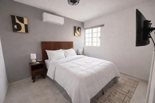a bedroom with a large white bed and a television at Private Apartment in Prague Poniente Area in Hermosillo