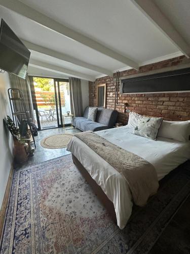 a bedroom with a large bed and a brick wall at RElaxed city living in Port Elizabeth