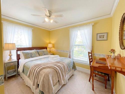 a bedroom with a bed with a ceiling fan and a desk at Strathaird Bed and Breakfast in Niagara Falls