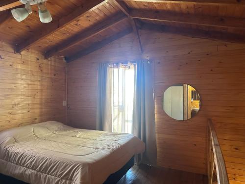 a bedroom with a bed and a mirror and a window at La cabaña de Noe in San Clemente del Tuyú