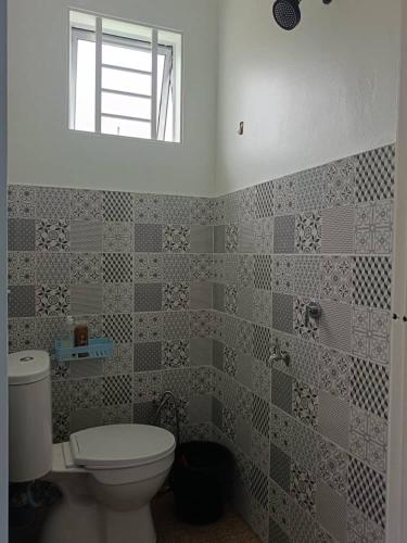 a bathroom with a toilet and a window at All Rushd Private Pool Homestay in Sungai Besar