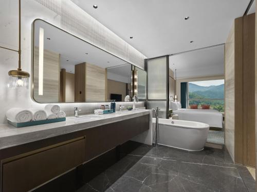 a bathroom with a tub and a large mirror at Hilton Zhuhai in Zhuhai