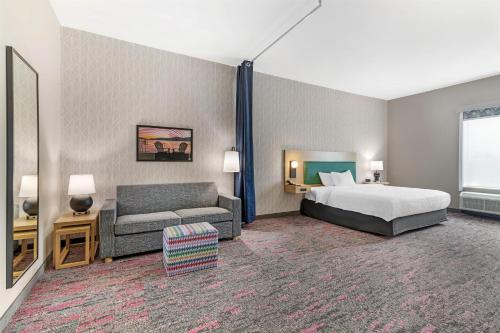 a hotel room with a bed and a couch at Home2 Suites by Hilton Queensbury Lake George in Queensbury