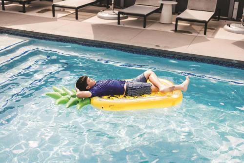 a young boy laying on a raft in a swimming pool at Hyatt Regency Frisco-Dallas in Frisco